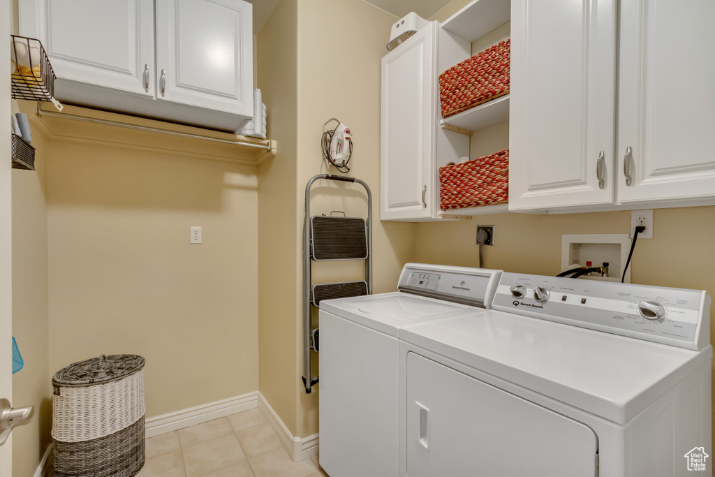 Washroom featuring baseboards, cabinet space, separate washer and dryer, and light tile patterned flooring