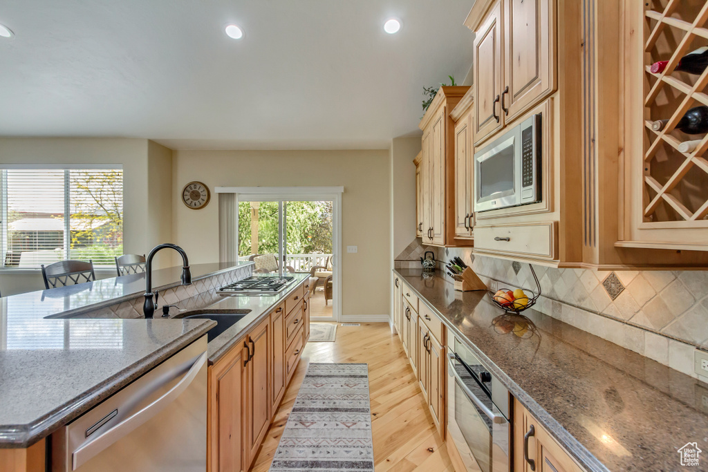 Kitchen with recessed lighting, a kitchen island with sink, appliances with stainless steel finishes, a sink, and light wood-type flooring