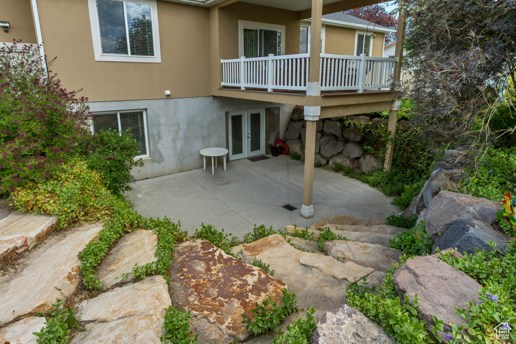 Exterior space with a deck, french doors, stucco siding, and a patio area
