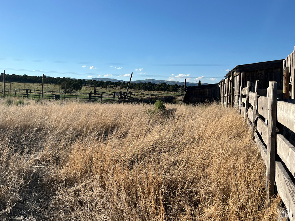 View of yard with fence, a rural view, and a mountain view