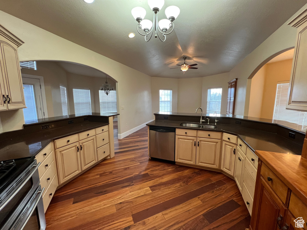 Kitchen featuring a sink, stainless steel appliances, dark wood-style floors, arched walkways, and a peninsula