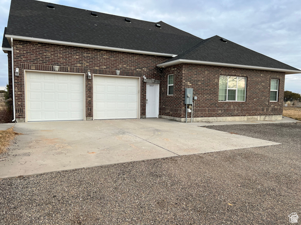 Exterior space featuring brick siding, a shingled roof, concrete driveway, and an attached garage