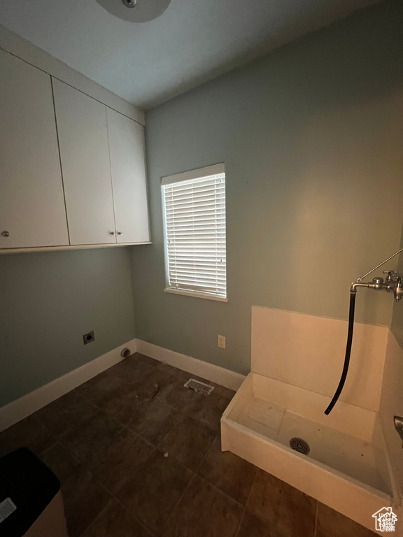 Interior space with baseboards, visible vents, cabinet space, and dark tile patterned flooring