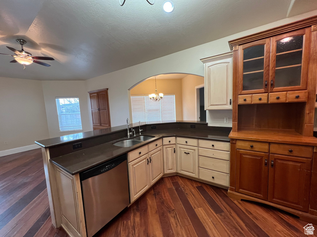 Kitchen with dark wood finished floors, a sink, stainless steel dishwasher, arched walkways, and ceiling fan with notable chandelier
