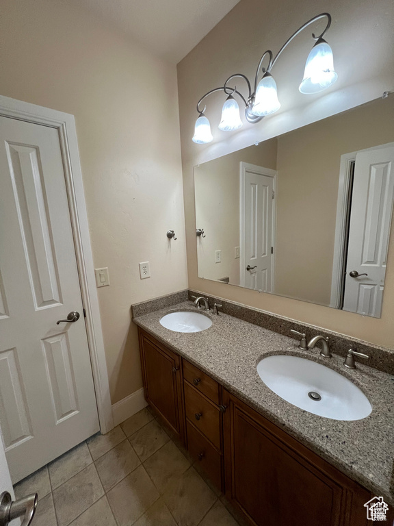 Bathroom with tile patterned flooring, a sink, double vanity, and baseboards