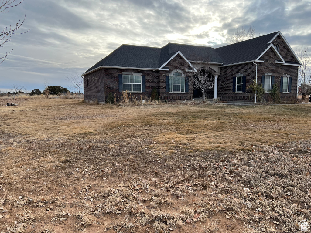 View of front of home featuring brick siding and roof with shingles