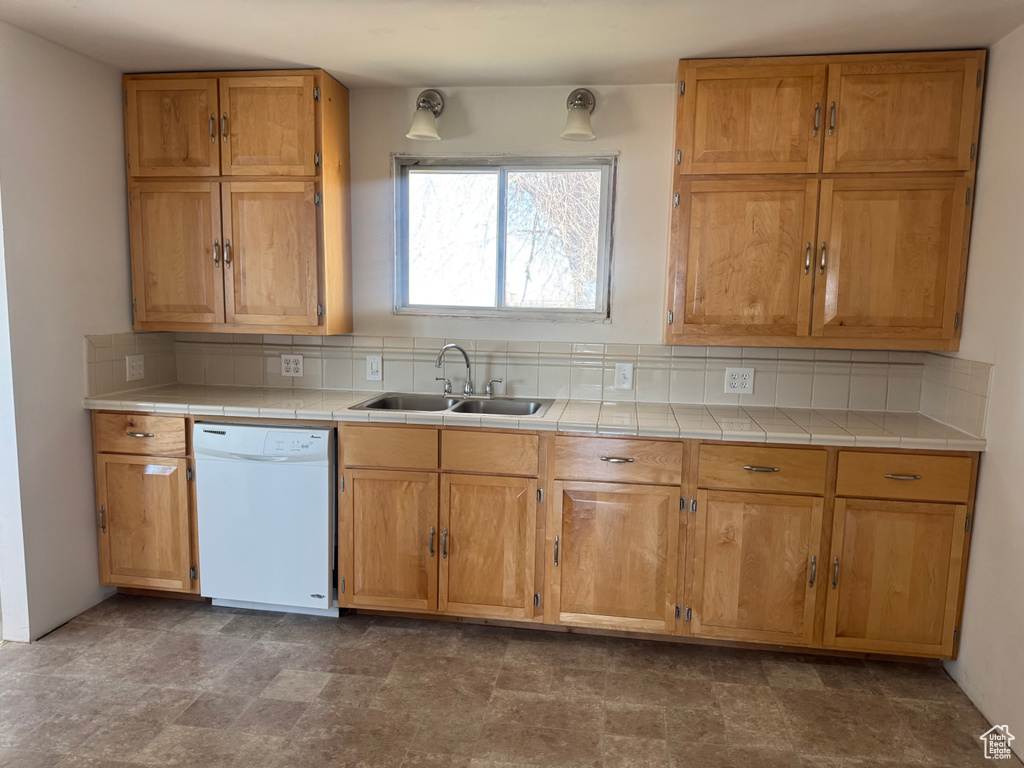 Kitchen with tile counters, tasteful backsplash, white dishwasher, and a sink