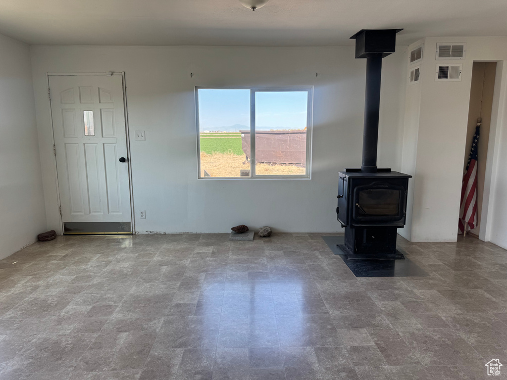 Unfurnished living room featuring visible vents and a wood stove