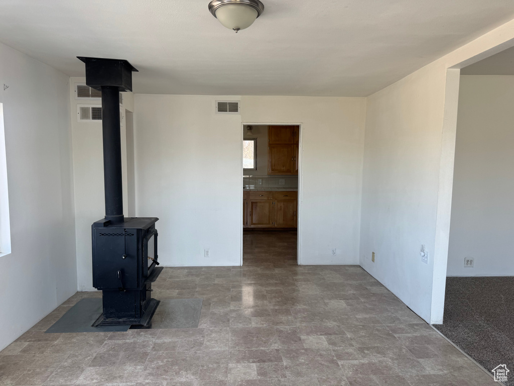 Unfurnished living room featuring stone finish flooring, a wood stove, and visible vents