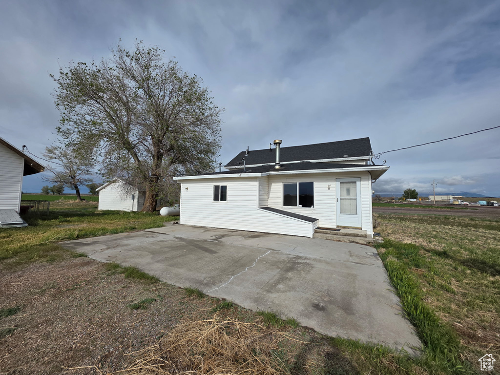Rear view of property featuring a patio, a lawn, and an outbuilding
