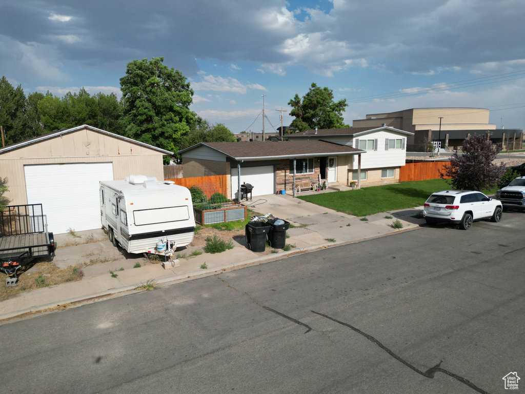 Tri-level home featuring a detached garage, fence, and a front lawn