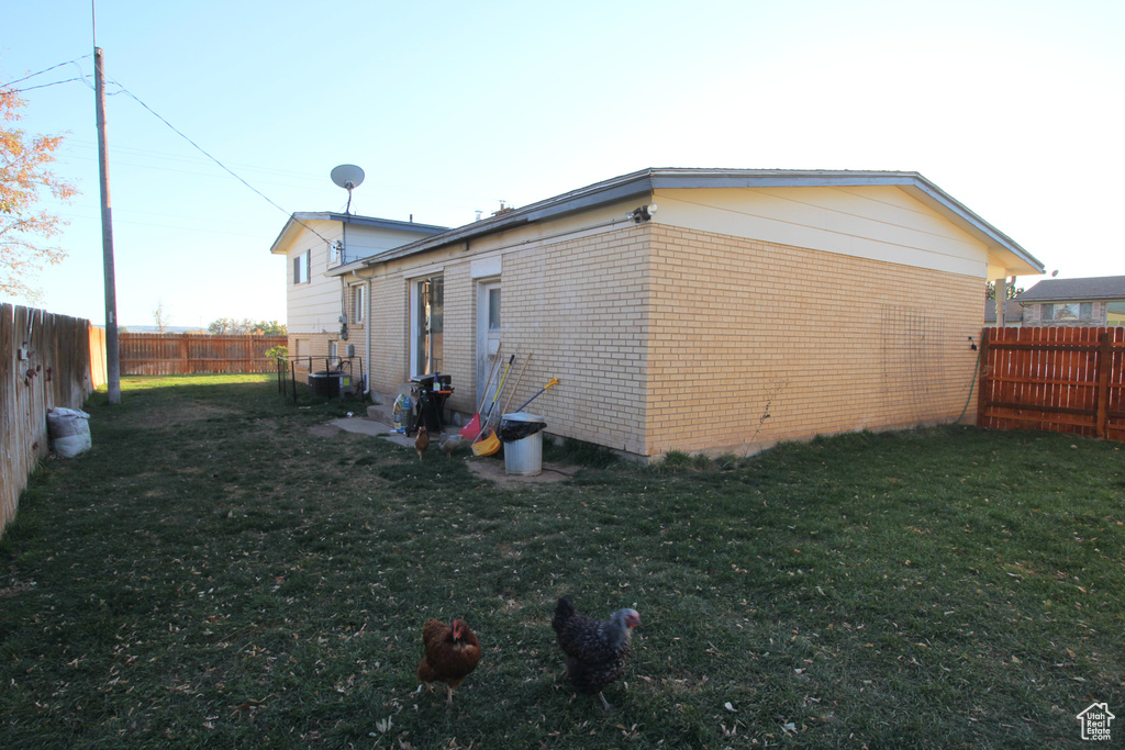 View of side of property featuring a yard, a fenced backyard, and brick siding