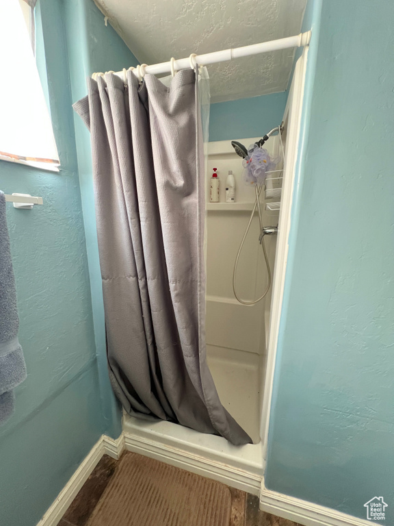 Bathroom featuring baseboards, a shower stall, and a textured ceiling
