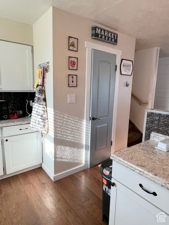 Kitchen featuring white cabinets, light stone countertops, and wood-type flooring