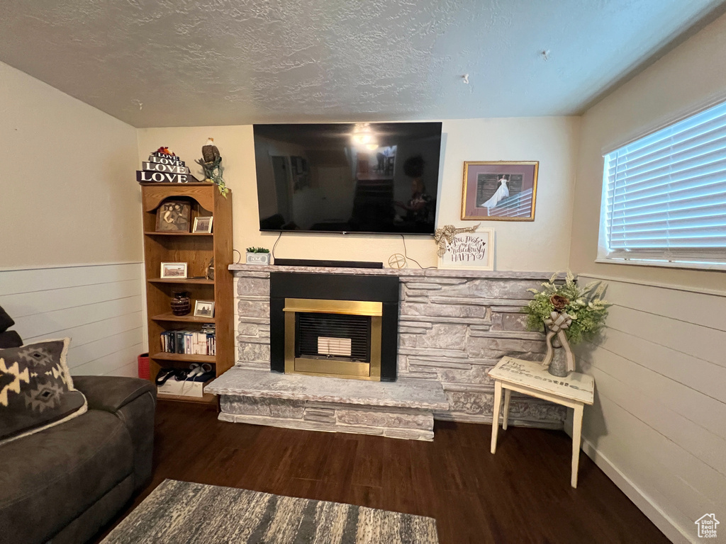 Living area featuring a fireplace, wooden walls, a wainscoted wall, a textured ceiling, and wood finished floors