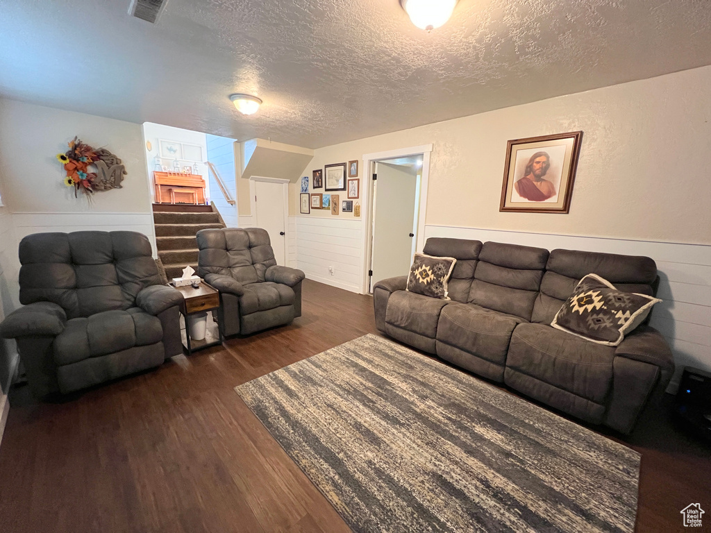 Living area featuring stairway, wainscoting, a textured ceiling, and dark wood-type flooring