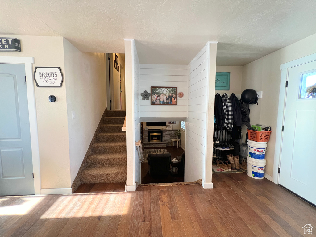 Stairs with a fireplace, a textured ceiling, wood finished floors, and baseboards
