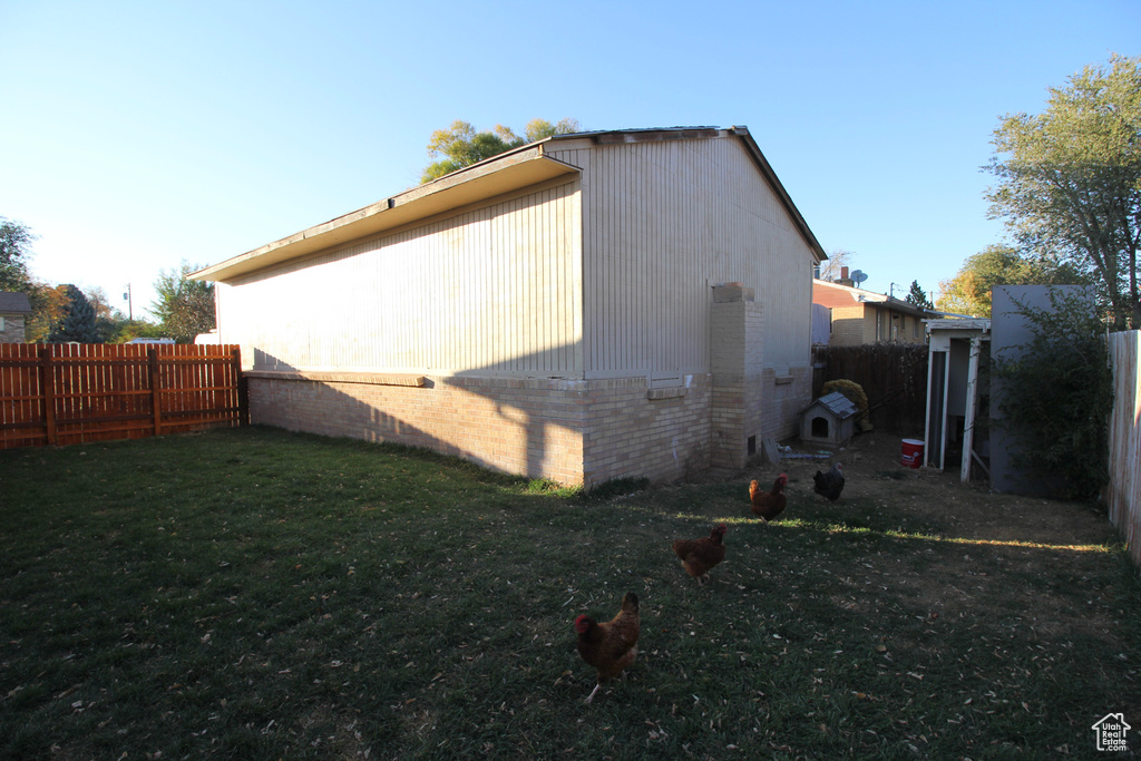 View of property exterior with a yard, a fenced backyard, and brick siding