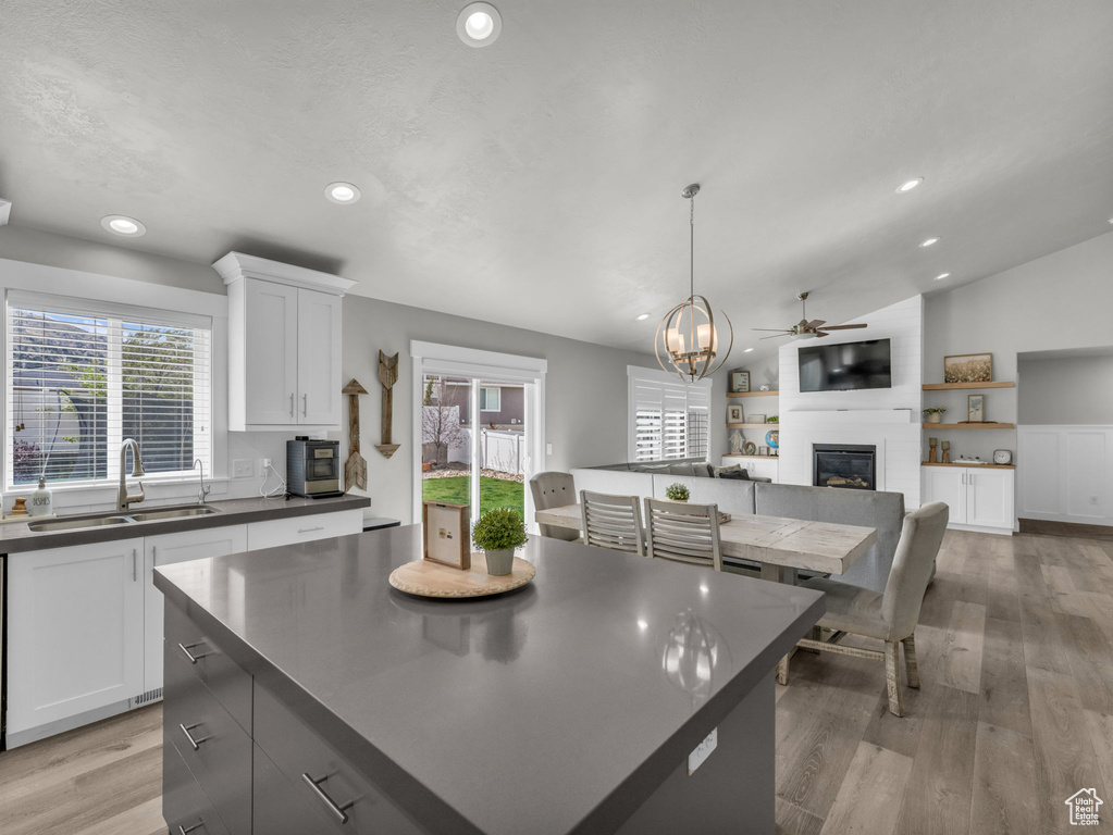 Kitchen featuring recessed lighting, a large fireplace, ceiling fan with notable chandelier, dark countertops, and a sink