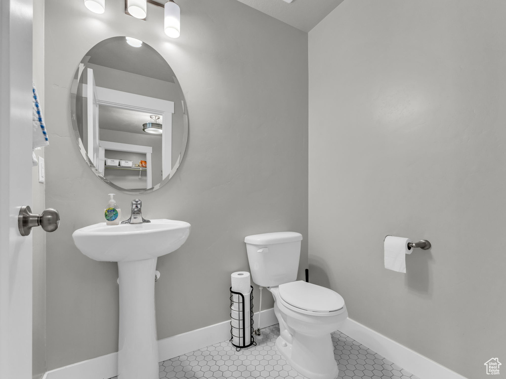 Half bath with toilet, a sink, and baseboards
