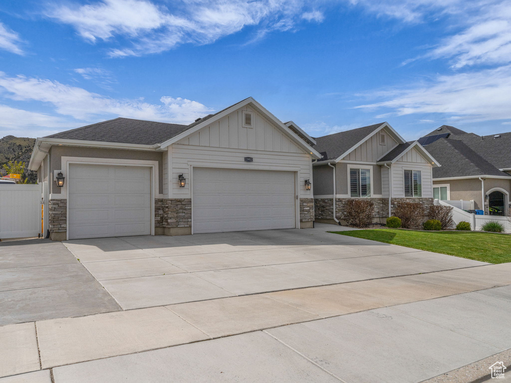 Craftsman-style house featuring driveway, board and batten siding, an attached garage, and stone siding