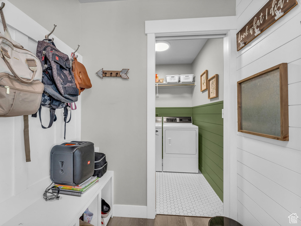 Washroom featuring wood finished floors, laundry area, and washing machine and dryer