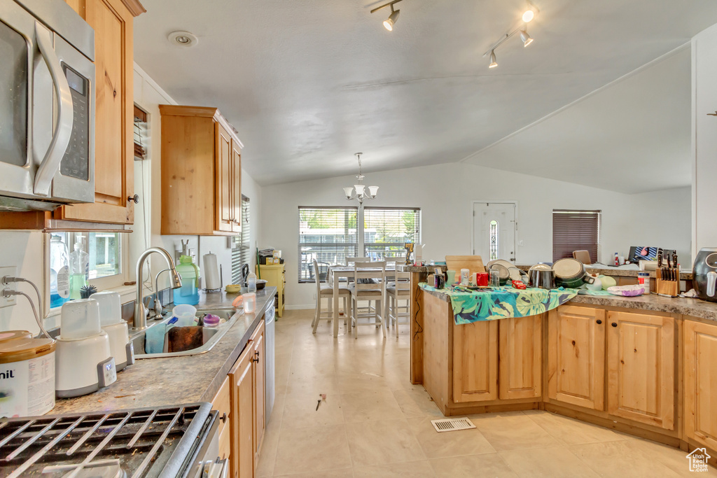 Kitchen with a sink, a chandelier, lofted ceiling, and light countertops