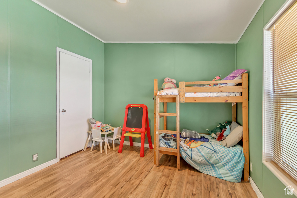 Bedroom featuring wood finished floors, ornamental molding, and multiple windows