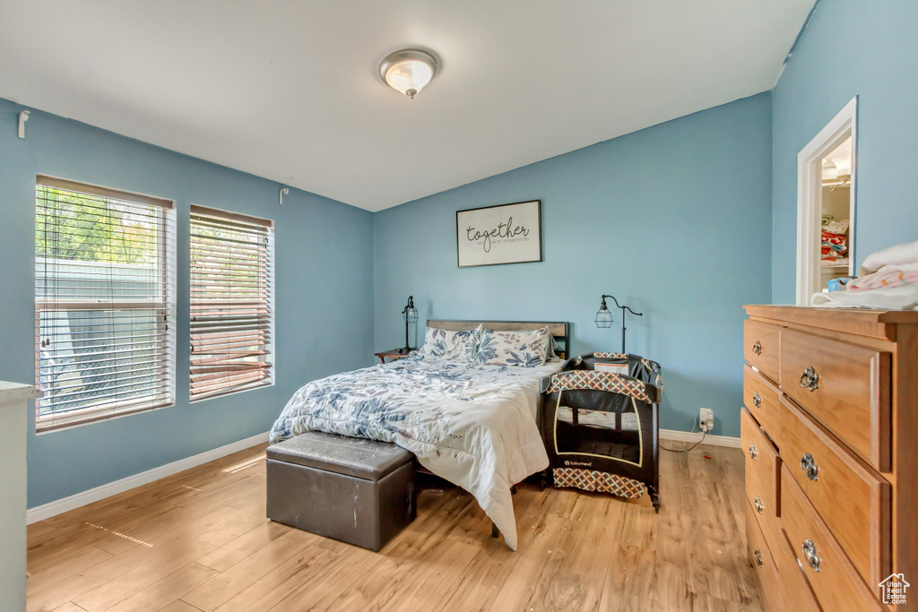 Bedroom with light wood finished floors, lofted ceiling, and baseboards
