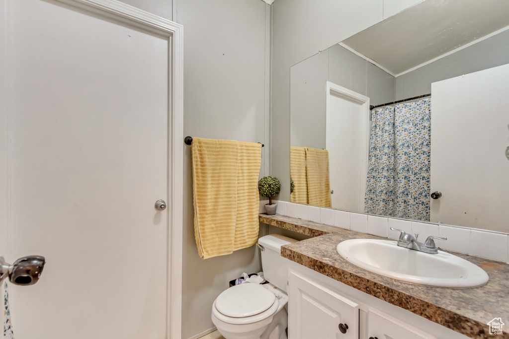 Bathroom featuring toilet, curtained shower, and vanity