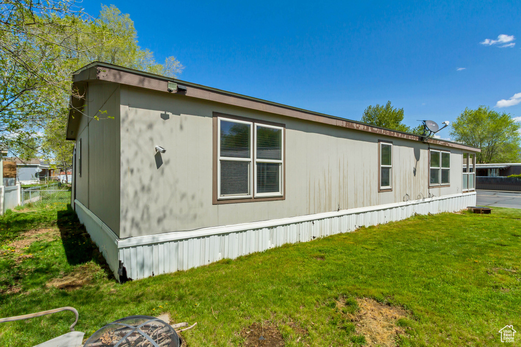 View of side of home featuring a yard and fence