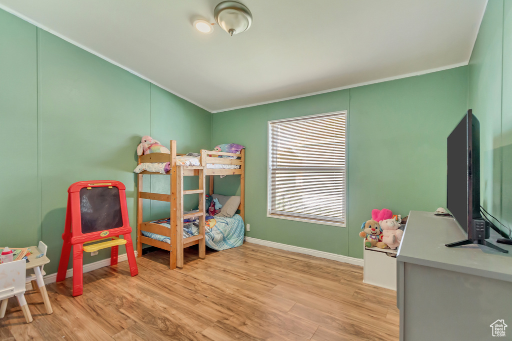 Bedroom featuring baseboards, crown molding, and light wood-style flooring