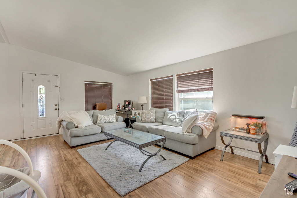 Living area featuring baseboards, a healthy amount of sunlight, lofted ceiling, and light wood finished floors