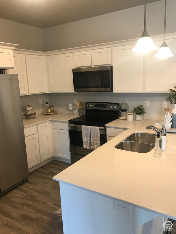 Kitchen featuring appliances with stainless steel finishes, light countertops, dark wood-style flooring, a sink, and white cabinetry