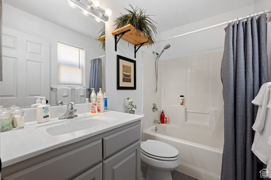 Bathroom with toilet, shower / bath combo with shower curtain, and vanity