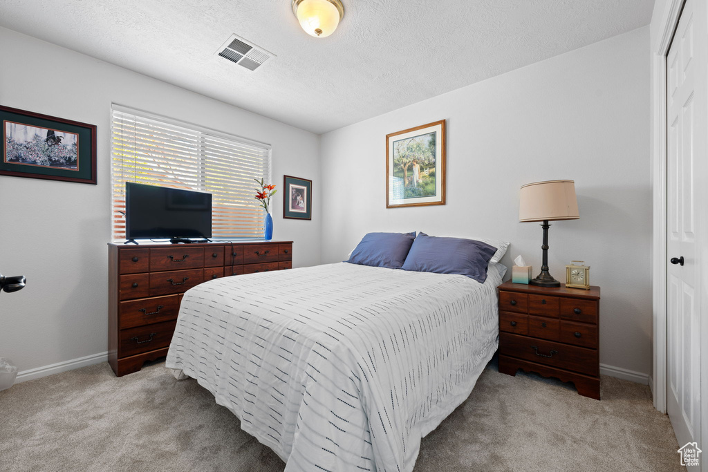 Bedroom featuring baseboards, visible vents, light carpet, and a closet