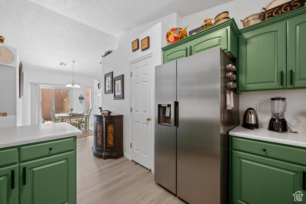 Kitchen featuring a textured ceiling, a chandelier, light countertops, light wood-type flooring, and stainless steel refrigerator with ice dispenser