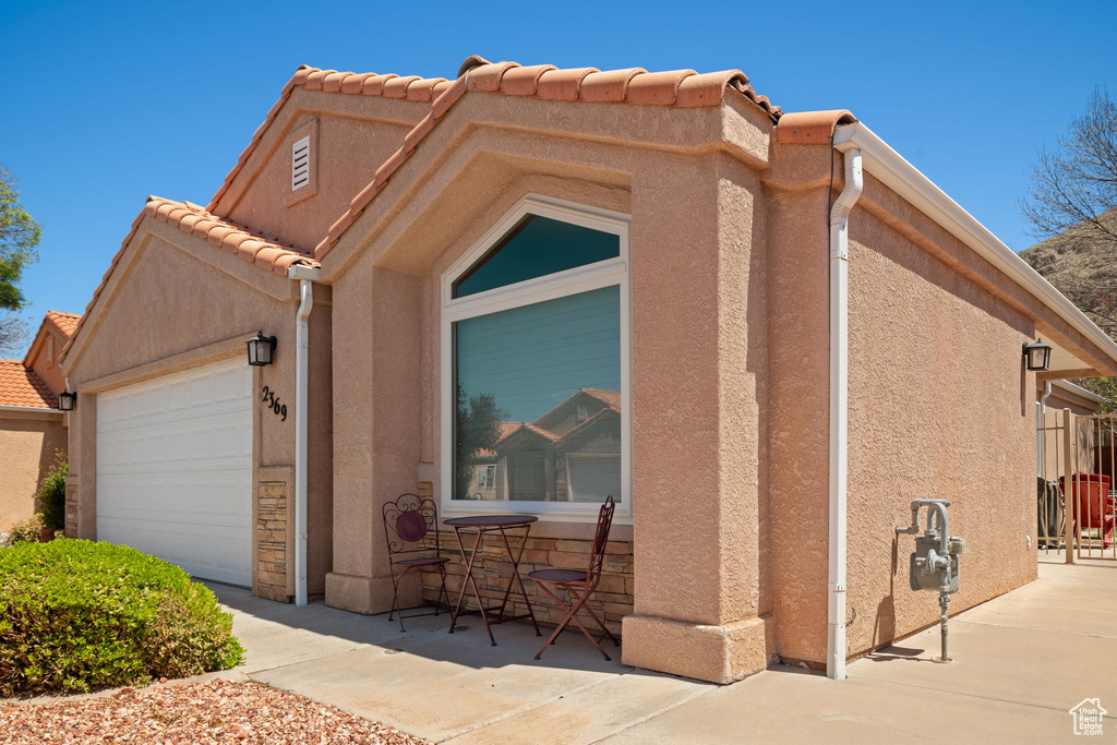 Exterior space with stucco siding, an attached garage, and a tile roof