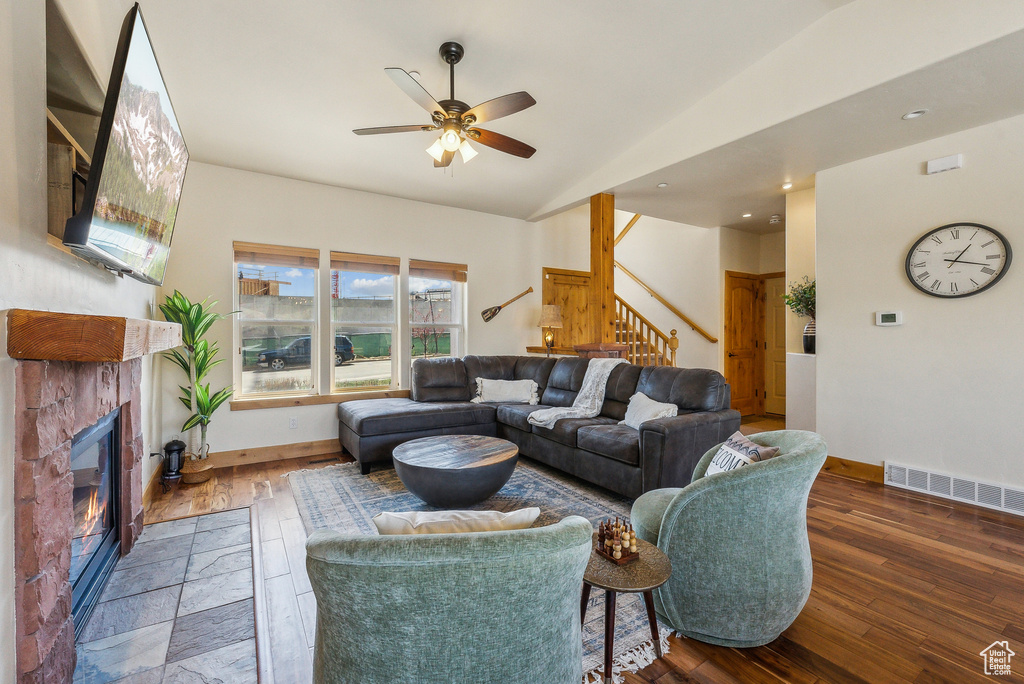 Living area featuring wood-type flooring, stairs, visible vents, vaulted ceiling, and baseboards