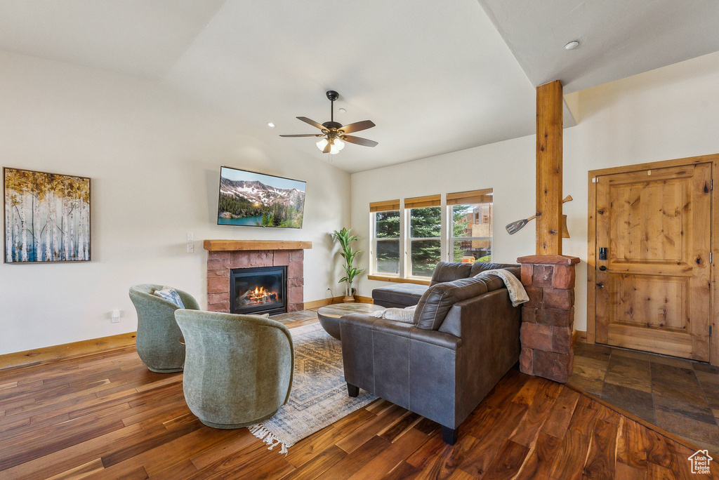 Living area with baseboards, a glass covered fireplace, vaulted ceiling, dark wood finished floors, and a ceiling fan