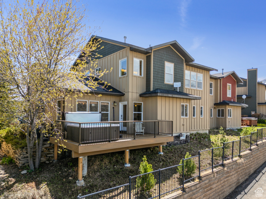 Back of property with board and batten siding, a wooden deck, and a fenced backyard