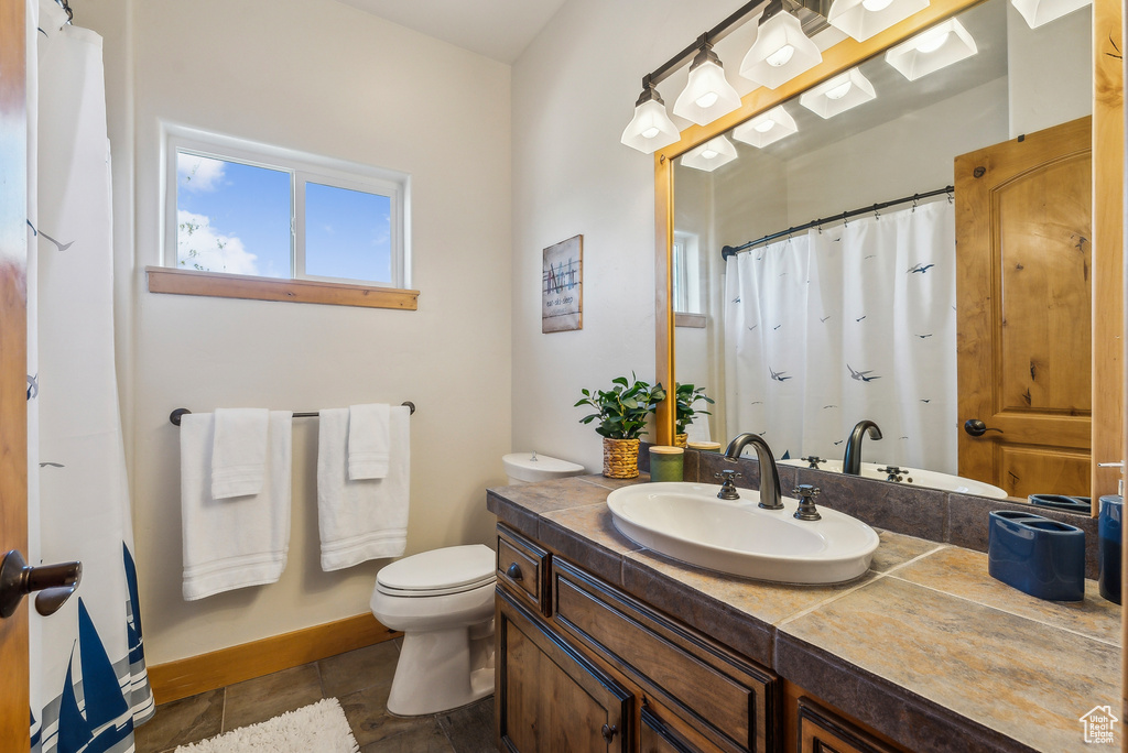 Full bathroom with vanity, toilet, a shower with shower curtain, and baseboards