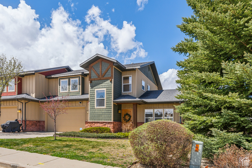 View of front facade featuring stone siding, board and batten siding, concrete driveway, and a garage