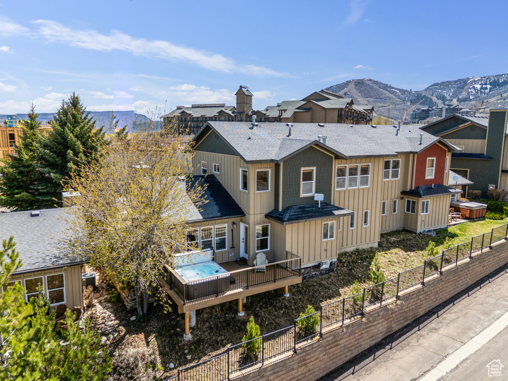 Rear view of property featuring a deck with mountain view, board and batten siding, a shingled roof, and a fenced backyard