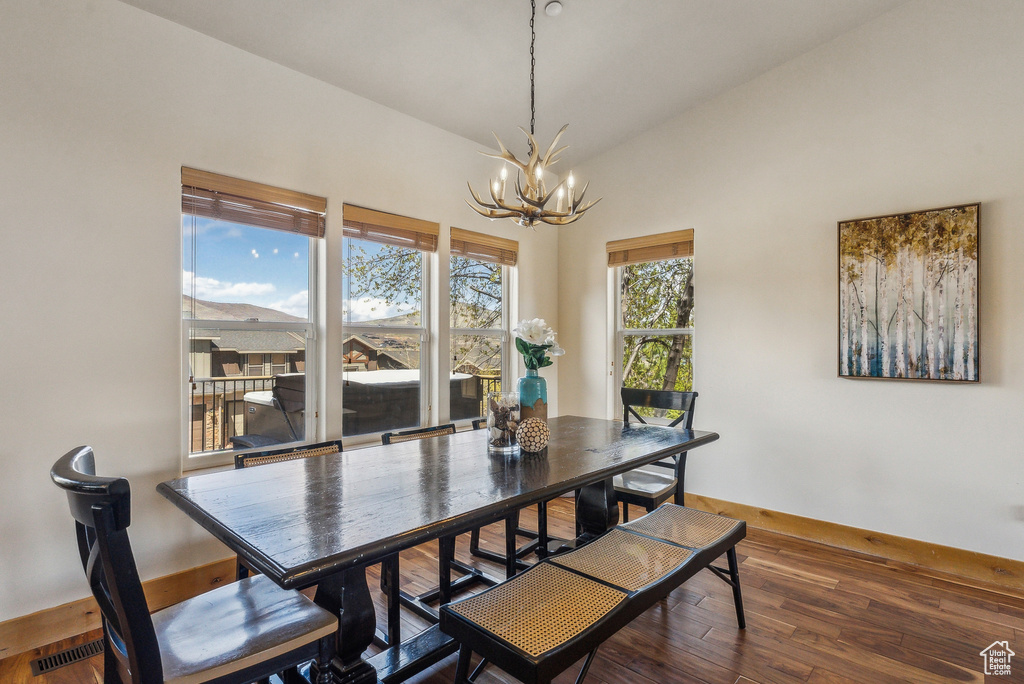 Dining room featuring lofted ceiling, a notable chandelier, wood finished floors, and baseboards
