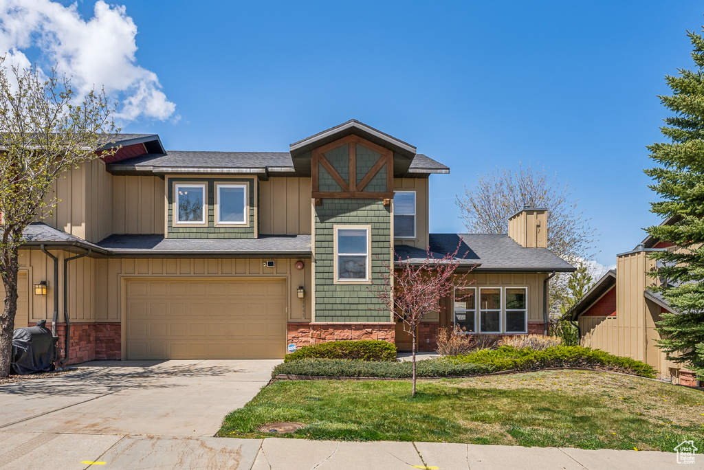 View of front of property featuring a chimney, a front lawn, driveway, and an attached garage