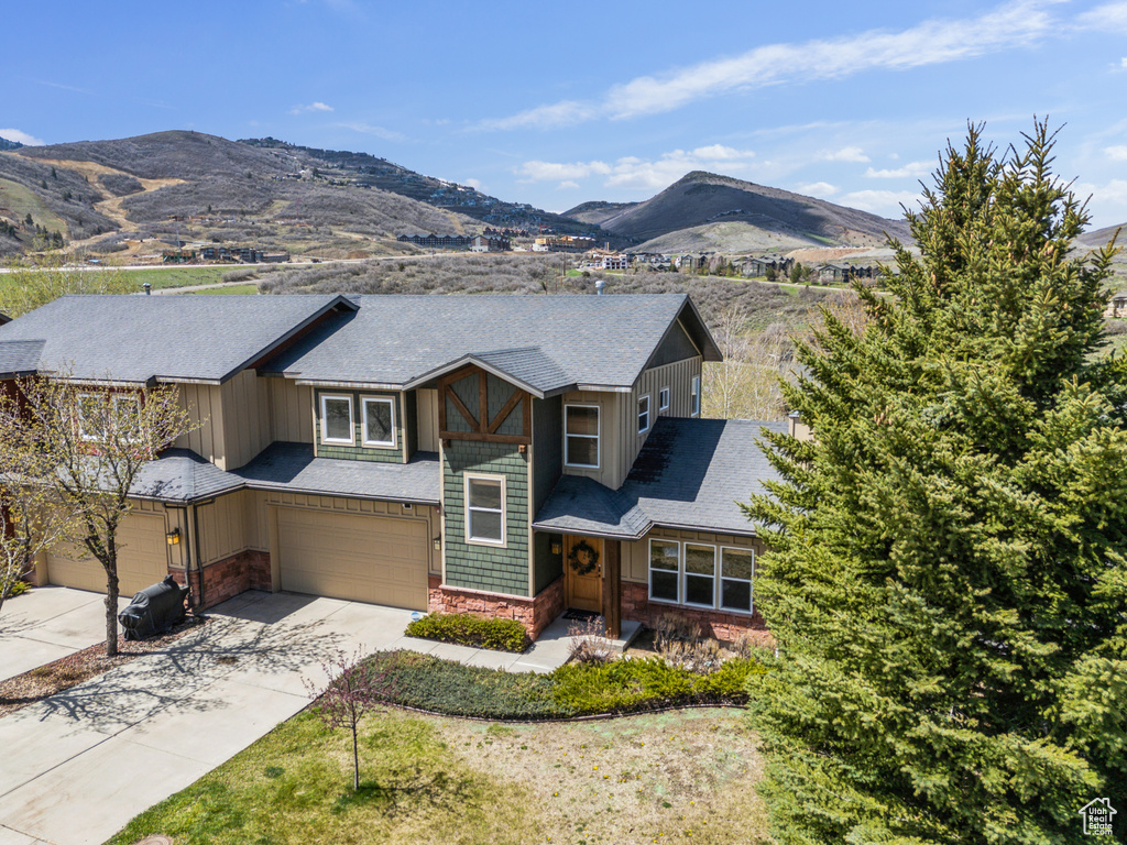 View of front of house featuring driveway, board and batten siding, stone siding, a mountain view, and an attached garage
