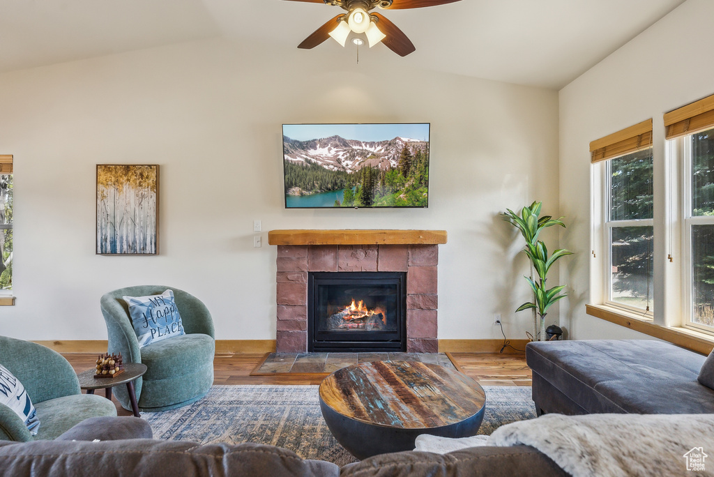 Living area featuring ceiling fan, wood finished floors, lofted ceiling, and a fireplace