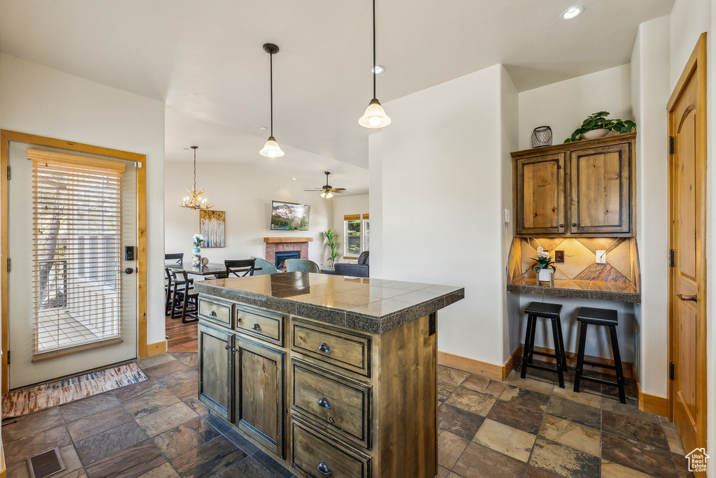 Kitchen featuring ceiling fan, visible vents, tile counters, and stone tile flooring