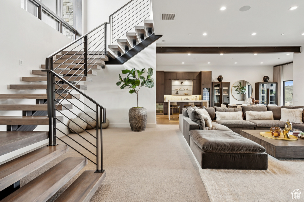 Living room featuring stairway, visible vents, recessed lighting, and light carpet